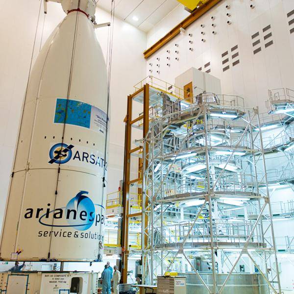 The nose cone of a rocket stands in a factory with a five-storey ramp next to it