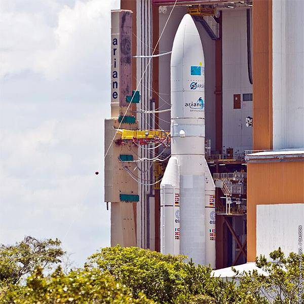 A view over treetops of a rocket sitting on the launchpad before lift off