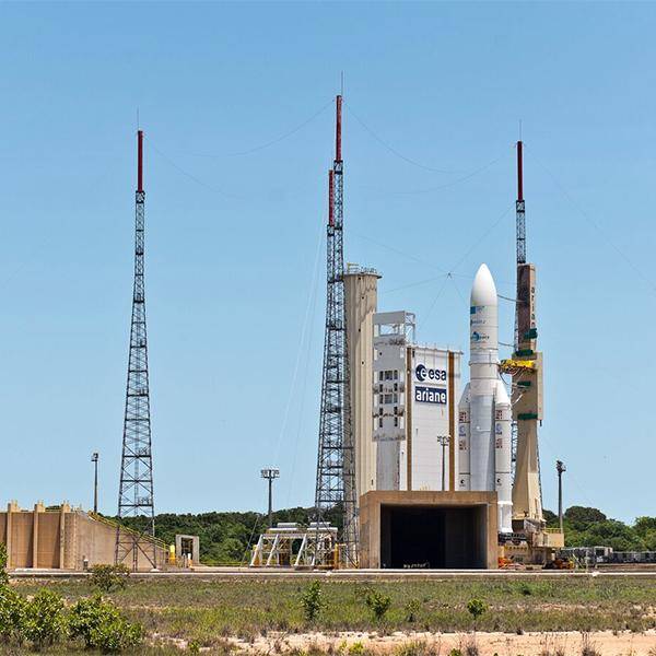 A rocket sits on a launchpad, ready for takeoff against a clear blue sky