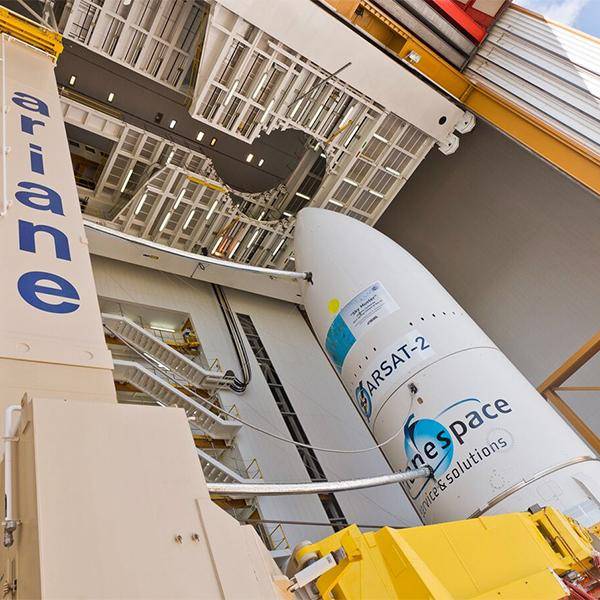 The nose cone of a rocket with 'ariane' branding and 'ARSAT-2' written on it